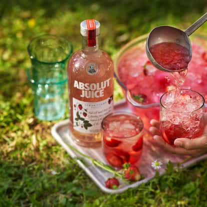 Absolut Juice Strawberry Spritz in a rocks glass with crushed ice and strawberry slices.