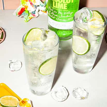 Absolut Lime Fizzy in a highball glass with lime slices and ice on white background