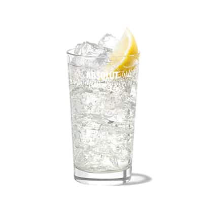 Absolut Ps in a highball glass with ice and a lemon wedge on white background