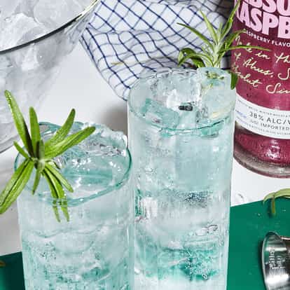 Absolut Raspberri Highball in two highball glasses with crushed ice and rosemary sprigs