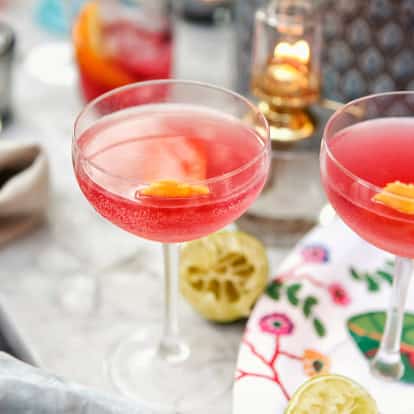 Absolut Raspberripolitan in two coupe glasses with orange peel garnishes