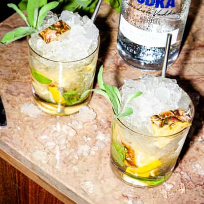 Smoked Pineapple Smash cocktail next to a bottle of Absolut Vodka.