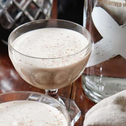 Absolut Vanilia Alexander in coupe glasses topped with nutmeg beside a vodka bottle