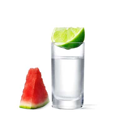Absolut Watermelon Shot served in a shot glass with lime wedge on rim and watermelon wedge beside on white background