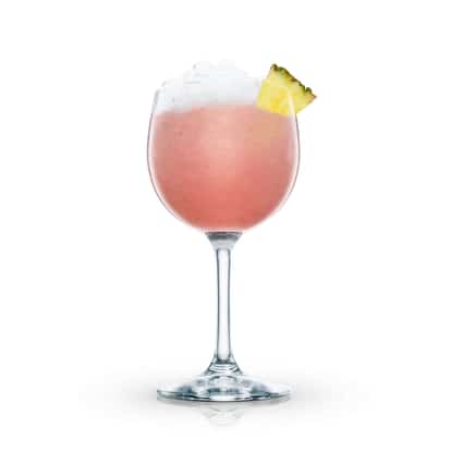 Batida Rosa in a stemmed wine glass topped with crushed ice and a pineapple wedge