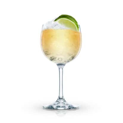 Beverly Hills Iced Tea in a stemmed wine glass with ice and a lime wedge on white background
