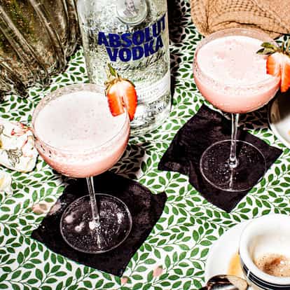 Black Forest Gateau Martini in two coupes garnished with strawberry and an Absolut Vodka bottle on table