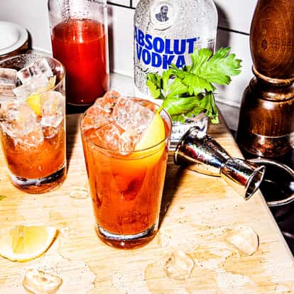 Two classic Bloody Mary cocktails made with Absolut Vodka and garnished with a lemon wedge and a celery stick