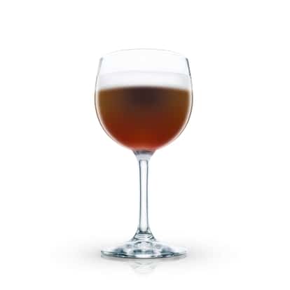 Café Dom served in a stemmed wine glass with a foam layer on white background