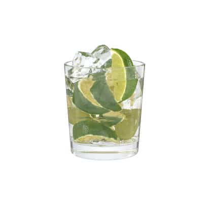 Caipiruva in a rocks glass with ice and lime wedges on white background