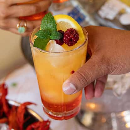 Campari Nobile in a highball glass with ice lemon wedge mint sprig and raspberries