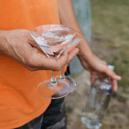 A man from the neck down in an orange t-shirt holds a Chocolate Martini in a coupe glass.