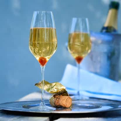 Classic Champagne Cocktail in two champagne flutes with sugar cube garnish on a silver tray