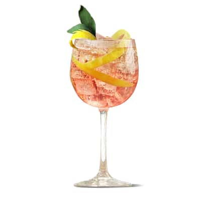 Concord Calling in a stemmed wine glass with ice, lemon twist and sage sprig on white background