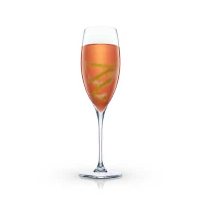 Devil’s Tail in a champagne flute with a spiral citrus peel on white background