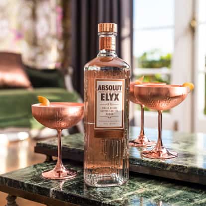 Fennel Countdown in a copper coupe with a lemon twist and an Absolut Elyx bottle on a marble table