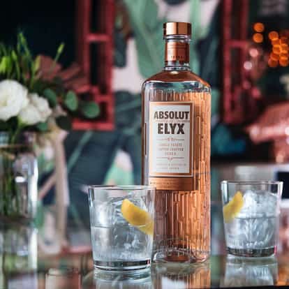Elyx On The Rock with an Absolut Elyx bottle and two rocks glasses with ice and lemon peel on a mirrored bar surface