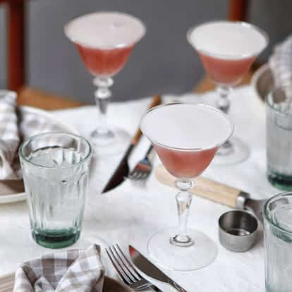 Es Saada served in coupe glasses with an Absolut Mandrin bottle and metal shaker on table