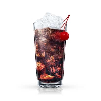 Factory Cola in a highball glass with crushed ice and a maraschino cherry on white background