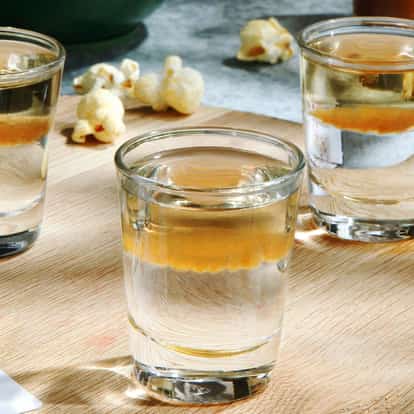 Flatliner in three shot glasses on a round wooden board with popcorn and playing cards