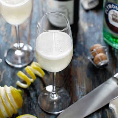 French 75 cocktail next to a bottle of Plymouth Gin.