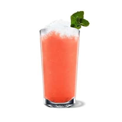 Fresh Watermelon Limeade in a highball glass with crushed ice and a mint sprig on white background