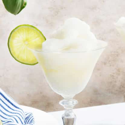 Frozen Daiquiri in two stemmed coupe glasses with lime wheels