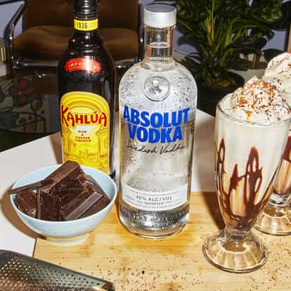 Two Frozen Mudslide cocktals next to a bottle of Absolut Vodka.