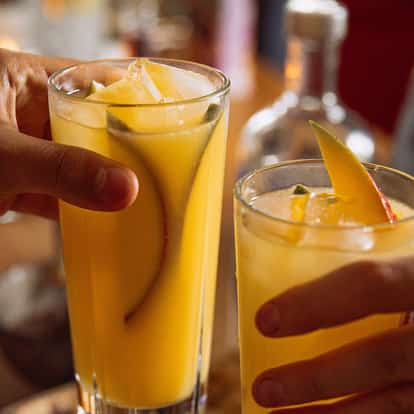 Golden Queen served in two highball glasses with ice and fruit slices