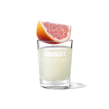 Grapefruit Drop Shot in an Absolut shot glass with sugared grapefruit wedge on rim on white background