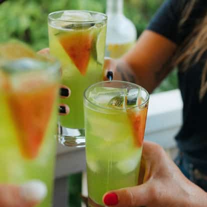 Green Peace in three tall highball glasses with ice and fruit wedge garnishes