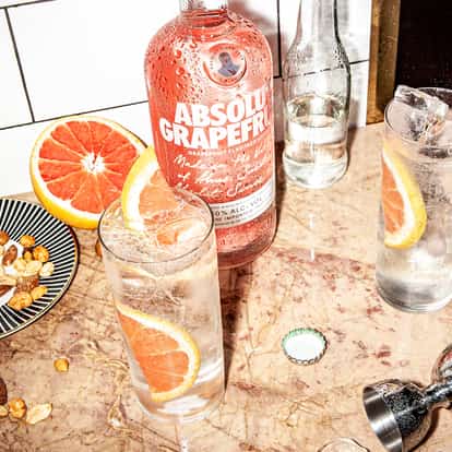 Hard Seltzer Grapefruit Drink in two highball glasses with ice and grapefruit slices plus an Absolut Grapefruit bottle