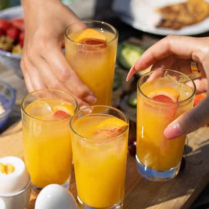 Harvey Wallbanger in four highball glasses with ice and citrus slice garnishes on a wooden board