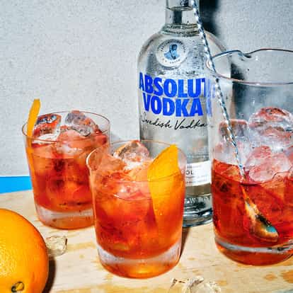 Hollis in two iced rocks glasses garnished with orange peel and a mixing glass with spoon and an Absolut Vodka bottle
