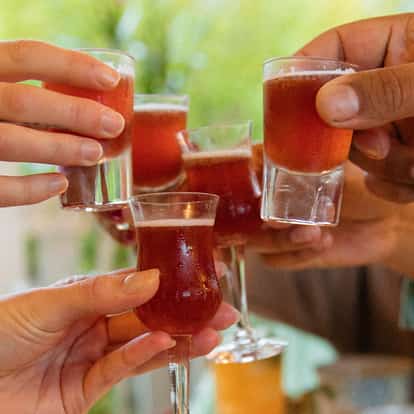 Illusion served in multiple shot and tulip glasses held aloft in a group toast