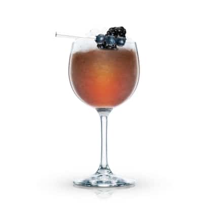 Jamaican Cobbler in a stemmed wine glass with crushed ice and blackberry and blueberries on a pick on white background