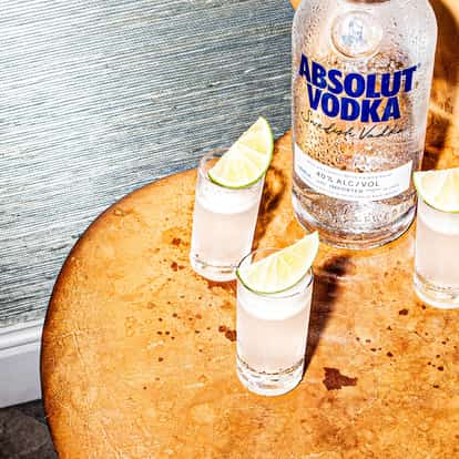 Four kamekaazi shots next to a bottle of Absolut Vodka.