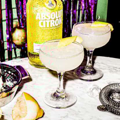 Two Lemon Drop Martini cocktails next to a bottle of Absolut Citron vodka