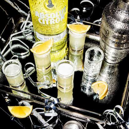 Lemon Drop Shot served in sugar-rimmed shot glasses on a tray with an Absolut Citron bottle and lemon wedges