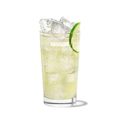Loretto Lemonade in an Absolut highball glass with ice and a lime wedge on white background