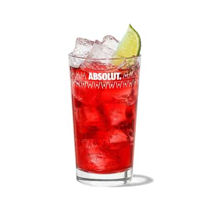 Malibu and Cranberry in an Absolut highball glass with ice and lime wedge on white background
