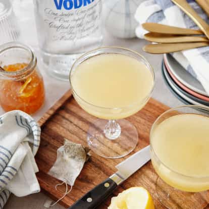 Marmalade Marteani in two coupe glasses on a wooden board with half a lemon and a jar of marmalade