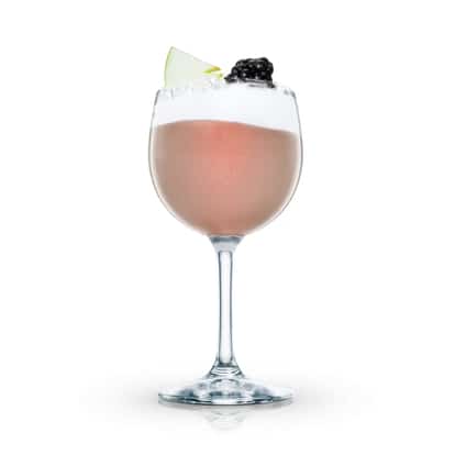 Marshall de Mure in a stemmed wine glass topped with foam and a blackberry and apple slice on white background