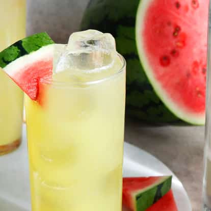 Melon Ball in a highball glass with ice and a watermelon wedge, Absolut vodka bottle at right