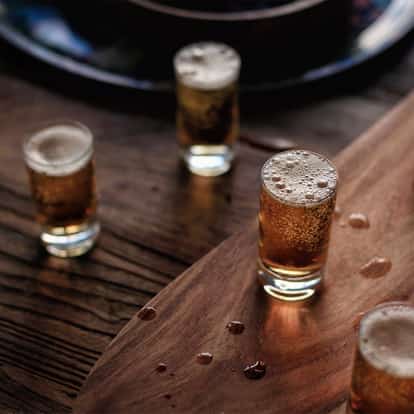 Mind Eraser Shot in several shot glasses on a wooden board with an Absolut Vodka bottle at left