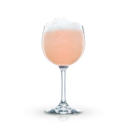 Papaya Sling in a stemmed wine glass with crushed ice on white background