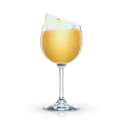 Parisian Spring Punch served in a stemmed wine glass with crushed ice and apple wedge garnish on white background
