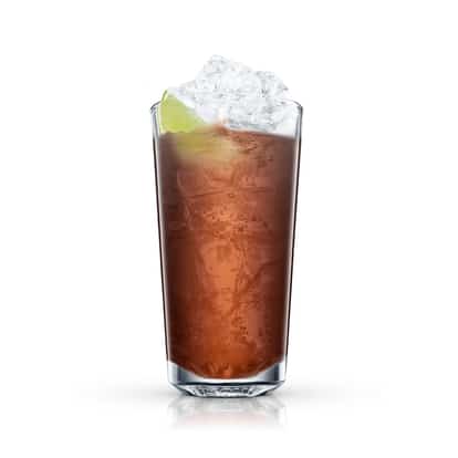 Tall highball glass with a brown mixed drink, crushed ice and a lime wedge on white background.