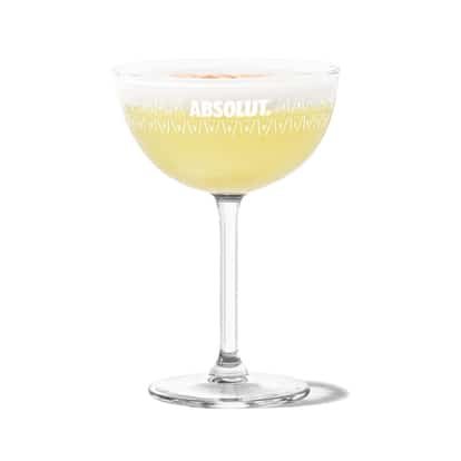 Pisco Sour in an Absolut coupe glass topped with egg white foam dotted with bitters on white background