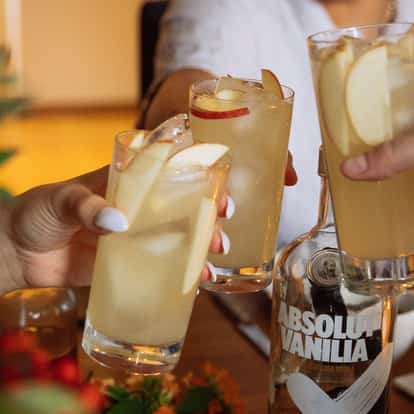 Pyl served in highball glasses garnished with apple slices with Absolut Vanilia bottle on table